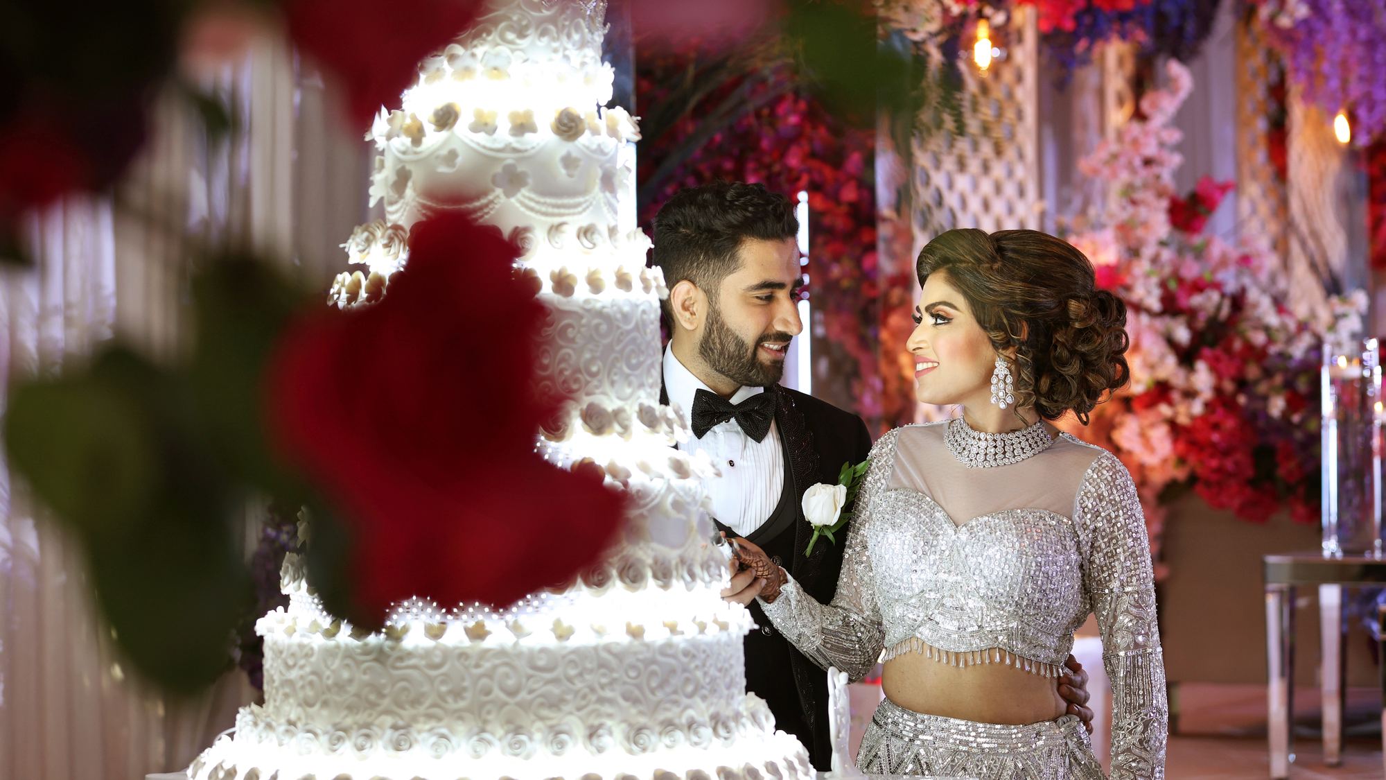 A bride and groom beside a tall wedding cake at the reception