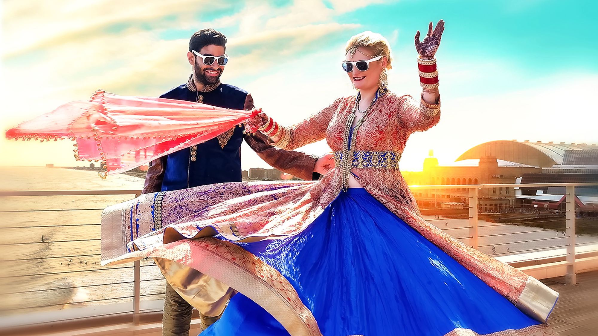 A couple dancing together with a dupatta against the evening sky
