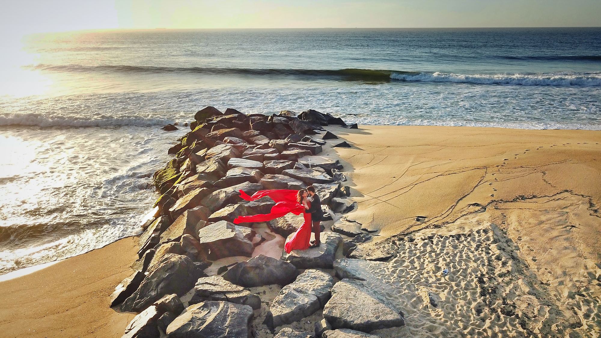 A red dupatta resting on the rocks of a beach jetty