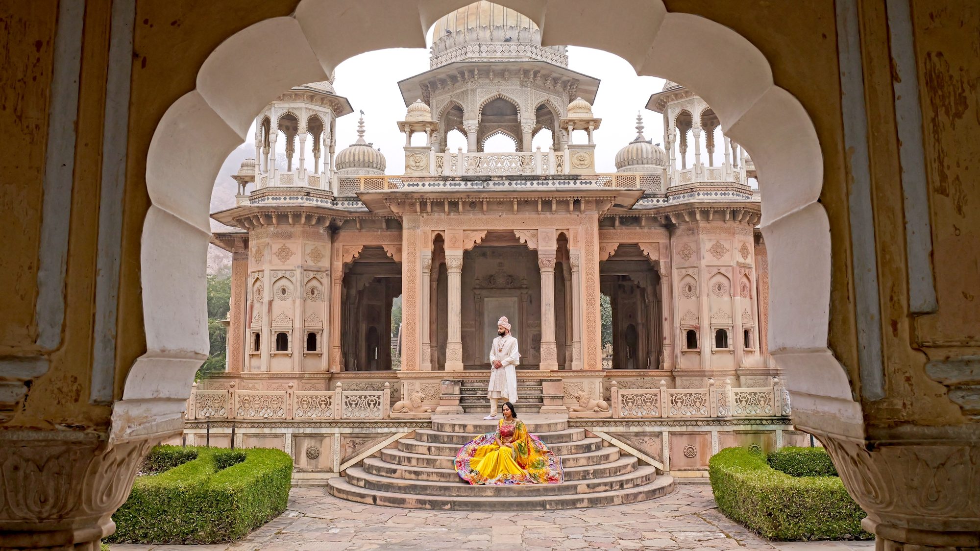 A bride and groom framed by a carved archway at a palace