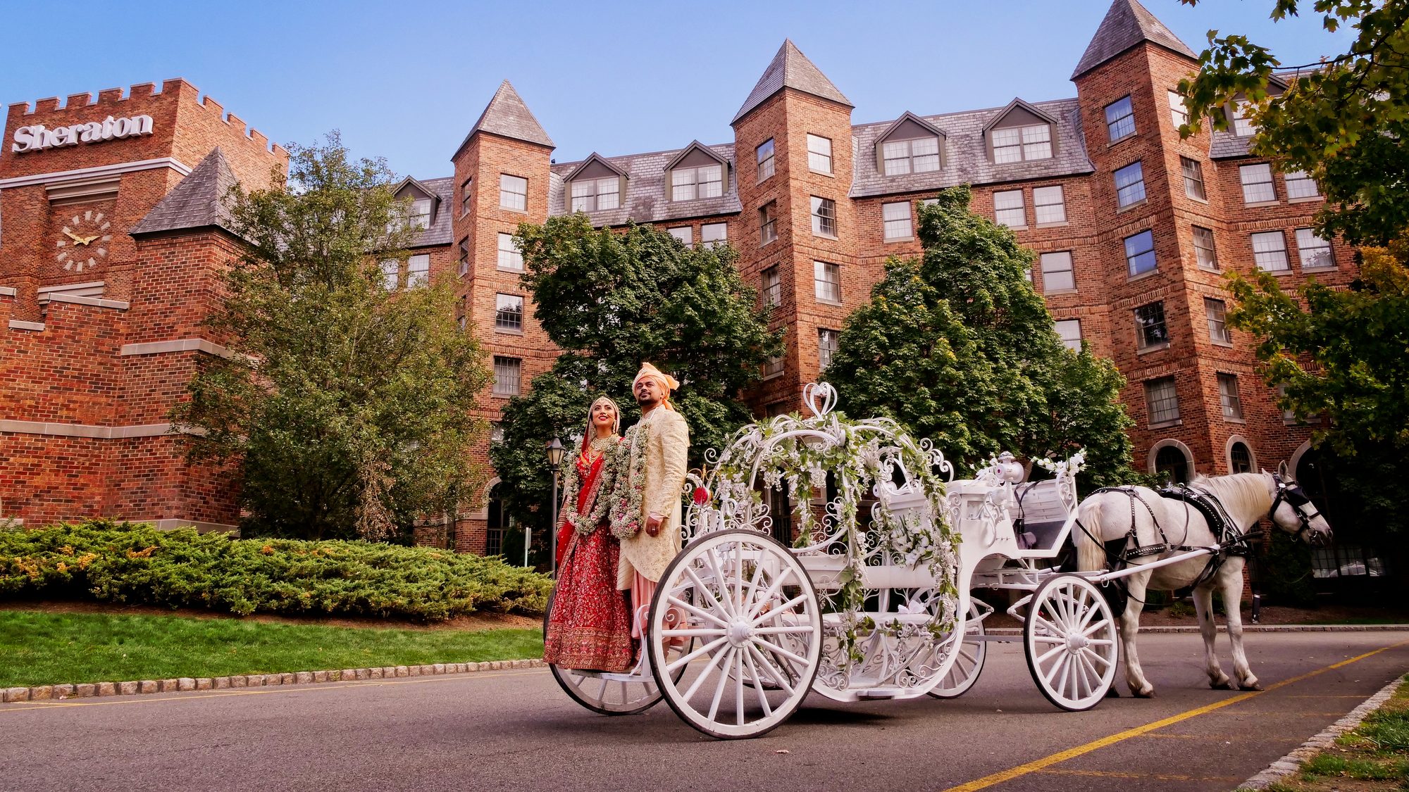 A bride and groom beside a horse-drawn carriage outside a hotel