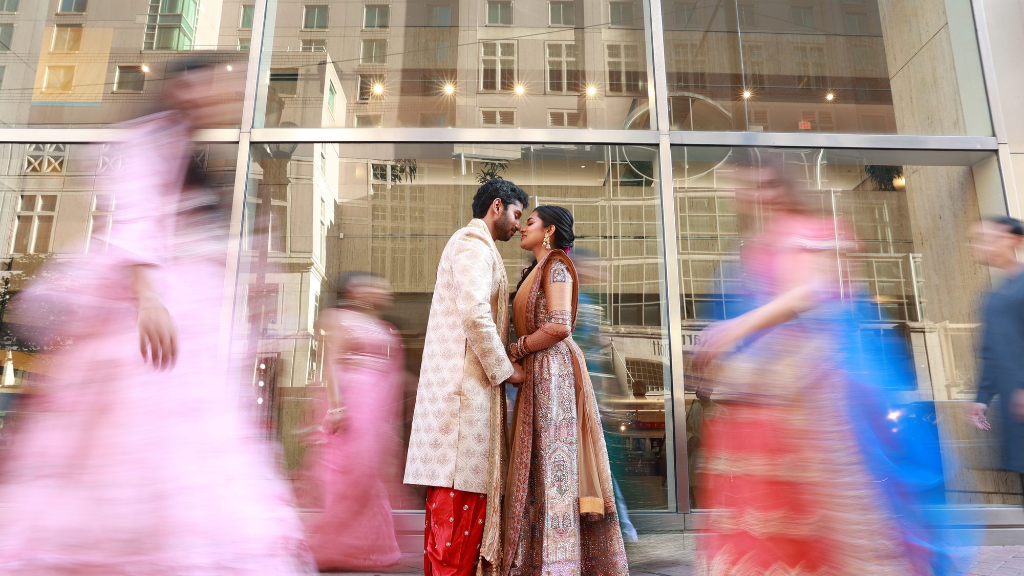 A bride and groom sharing a kiss as guests move past in a blur