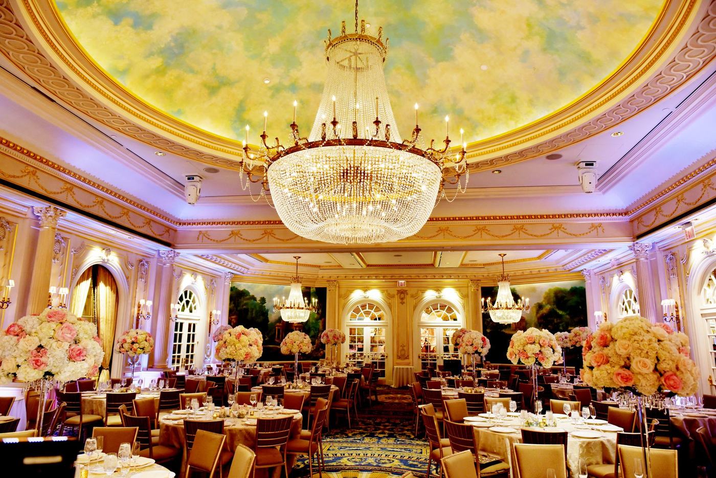 Ballroom with a painted sky ceiling and crystal chandeliers, set for a wedding