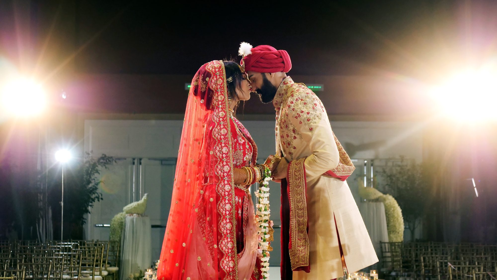 A bride and groom touching foreheads beneath warm stage lights